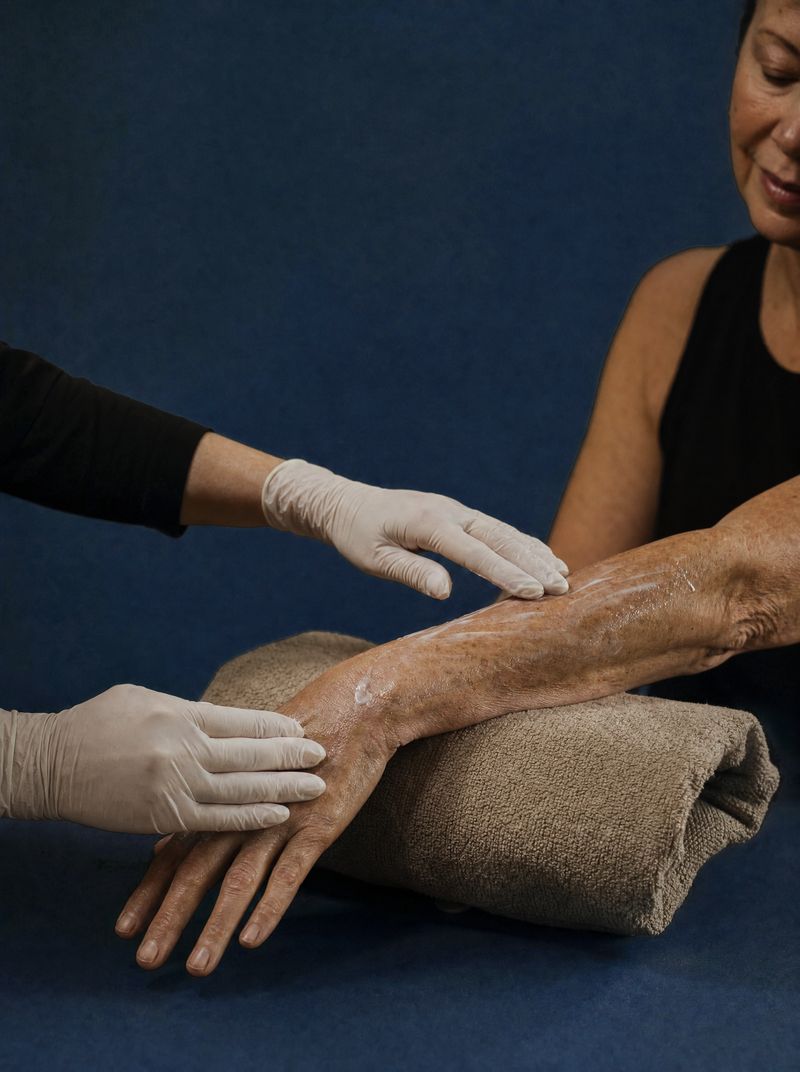 Gloved hands smoothing treatment cream onto a client’s forearm